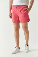 Short de baño liso de corte clásico, con cintura elástica ajustable mediante cordón. Cuenta con dos bolsillos laterales y uno trasero, confeccionado en tejido ligero de secado rápido con logo bordado.