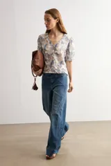 Camisa manga corta con estampado paisley en tonos azules y marrones, escote en V y cierre frontal con botones.