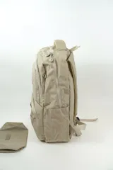Mochila beige de poliéster, con múltiples compartimentos con cierre, bolsillos frontales, bolsillos laterales y asa superior. Incluye un pequeño estuche a juego.