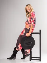 Vestido camisero largo con estampado floral en tonos rojos y negros, con cuello camisero, abotonadura frontal y mangas largas con puños abotonados.