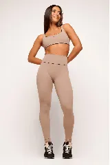 Top deportivo color beige con contorno negro, breteles anchos y logo pequeño en el frente.