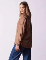 Camisa color verde oliva de lyocell, marca Cyrus. Tiene cuello con solapa, abertura central con botones, mangas 3/4 regulables con presilla y botón, y dos bolsillos delanteros aplicados.