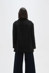 Chaqueta de corte holgado en color negro, con cuello solapa, cierre frontal con botones y bolsillos laterales.