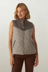 Chaleco de lana fina sin teñir con diseño acolchado en rombos y canesú en contraste. Cuenta con cuello alto, cierre frontal de cremallera y bolsillos laterales.