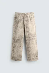 Pantalón de corte baggy fit confeccionado en tejido de algodón con efecto lavado y estampado abstracto en tonos beige y gris. Presenta diseño de cinco bolsillos, cierre frontal con cremallera y botón.