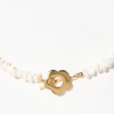 Collar corto de perlas de río con cierre de flor dorada.