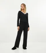 Conjunto de pijama negro de dos piezas, compuesto por una blusa de manga larga con escote en V y detalle de encaje blanco, y un pantalón largo de corte recto con cintura elástica.