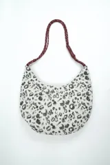 Cartera tipo hobo con estampado animal print en tonos blanco y gris, con correa de cuerda trenzada en color bordó.