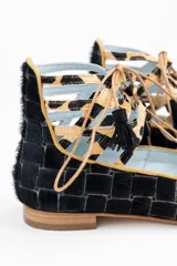 Botines bajos negros con diseño tejido y cordones con borlas. Presentan detalles de animal print en el tobillo y ribete ocre.