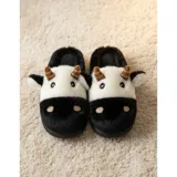 Pantuflas de peluche con diseño de vaca, confeccionadas en piel sintética suave. Cuentan con suela de goma antideslizante y diseño abierto en el talón.
