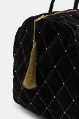 Bolso tipo shopper acolchado confeccionado en terciopelo negro. Presenta un diseño de rombos con hilo metalizado y aplicaciones de brillos en las intersecciones. Cuenta con doble asa de hombro, cierre superior con cremallera y detalle de pompón decorativo en el tirador.