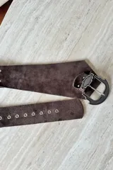 Faja ancha de gamuza vacuna color chocolate, con hebilla metálica de diseño labrado y ojales metálicos a lo largo de la tira.