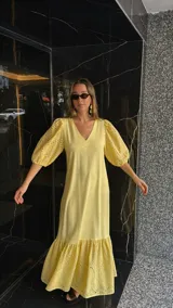 Vestido largo color amarillo pálido, con escote en V, mangas cortas abullonadas con detalle de calado y ruedo con volantes y calado.