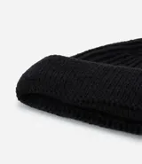 Gorro tipo fisherman de tejido acrílico con textura acanalada, diseño corto y etiqueta pequeña con logo en el frente.