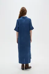 Túnica larga de viscosa azul, de corte holgado, con cuello camisero y cierre frontal de botones ocultos. Presenta mangas cortas con detalle de vuelta.