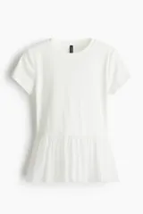 Top blanco ajustado de punto suave, con cuello redondo, manga corta y bajo con volados de tela.