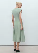 Vestido midi de corte evasé en color verde menta, con cuello en pico y mangas cortas. Presenta un diseño estructurado con costuras verticales visibles y cierre de cremallera en la parte posterior.