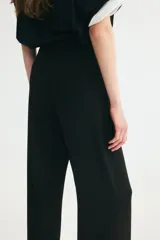 Pantalón sastrero de tiro alto y piernas amplias con pliegues en la parte delantera y trasera, en color negro.