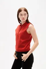 Chaleco de punto color rojo, con cuello polo y cierre frontal de botones. Diseño sin mangas y corte al cuerpo.