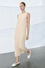 Vestido midi de viscosa con efecto arrugado, cuello redondo y diseño sin mangas. Presenta una sobrecapa superior con bordados detallados y entredoses, con cordones laterales ajustables terminados en borlas.