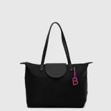 Tote bag de diseño minimalista color negro, confeccionada en material resistente al agua. Cuenta con doble asa de hombro, solapa frontal con el logo de la marca grabado y un dije colgante decorativo con la letra B en color fucsia.