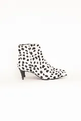 Bota de punta fina confeccionada en pelo sintético con estampado animal print tipo dálmata en blanco y negro, con taco fino medio.