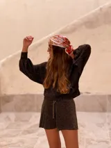 Buzo de tejido de punto con acabado brillante, confeccionado con hilado italiano. Presenta cuello redondo, mangas largas acampanadas y un corte holgado.