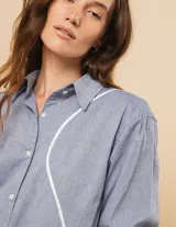 Camisa celeste de algodón con corte oversized, botones frontales a tono y vivos blancos ondulados en el frente.