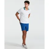 Polo de piqué blanco con cuello clásico y tapeta de dos botones. El cuello es blanco con rayas horizontales en verde, azul y negro. Tiene mangas cortas con ribete azul. Logo de pingüino bordado en el pecho.