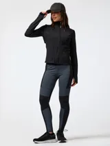 Campera deportiva negra de manga larga con cierre frontal y cuello alto, combinada con calzas grises y negras con diseño de paneles.