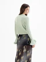 Cardigan negro de tejido de punto semi liviano, con calce al cuerpo, escote redondo y cierre frontal con botones. Mangas largas con puños godet acampanados que aportan volumen.