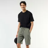 Bermuda verde militar de piqué de algodón con bolsillos cargo laterales y cordón ajustable en la cintura.