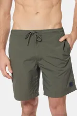 Bermuda de baño verde militar lisa, con bolsillos laterales y etiqueta con logo en la pierna.