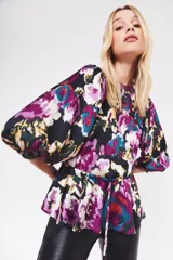 Camisa de satén con estampado floral abstracto en tonos violeta, fucsia, turquesa y negro. Presenta mangas abullonadas con puños elásticos y un ajuste en la cintura mediante cordón.