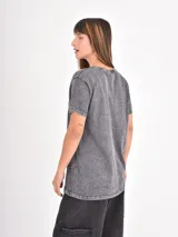 Remera de algodón con efecto acid wash en color gris oscuro, de corte holgado y manga corta. Presenta una estampa fotográfica en blanco y negro en el frente con la frase 'BLIND LOVE'.