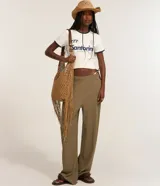 Remera estilo ringer de algodón color blanco crudo, con cuello redondo y ribetes en contraste azul marino en el cuello y mangas. Presenta un estampado frontal con la palabra "Santorini" y un gráfico estilizado.