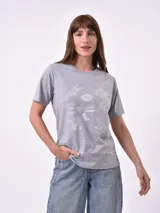 Remera de algodón gris jaspeado, corte clásico y cuello redondo, con estampado minimalista en blanco de elementos de playa y texto en francés.
