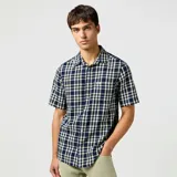 Camisa de manga corta a cuadros azules y blancos, con cuello clásico y bolsillo en el pecho.