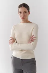 Buzo de morley color crema, con cuello bote y manga larga. Presenta un diseño de punto acanalado y un detalle de franja horizontal en el pecho.