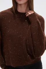 Polera de punto color marrón con destellos brillantes, cuello redondo, mangas largas abullonadas y diseño holgado.
