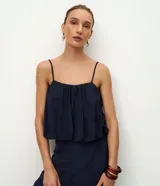 Blusa azul marino de viscosa con textura jacquard floral, escote recto y tirantes finos ajustables. Presenta diseño abullonado tipo globo con frunces que aportan volumen suave.