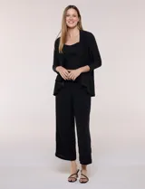 Cardigan negro de tejido elastizado con textura lisa, frente abierto sin botones y solapas amplias de caída drapeada. Cuenta con mangas tres cuartos y ruedo asimétrico.