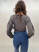 Remera negra de algodón con estampado dorado que simula un tejido o collar sobrepuesto. Presenta una moldería que realza los hombros y se entalla levemente hacia la cintura.