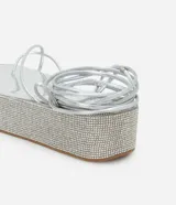Sandalias plateadas con plataforma flatform cubierta de strass, tiras finas y lazo para atar al tobillo.