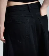 Falda larga de denim color negro, con corte evasé, cintura media, cierre frontal con botón y cremallera, bolsillos funcionales y bajo desflecado.