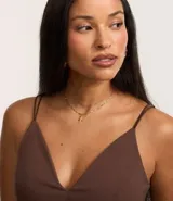 Top cropped color marrón con breteles finos dobles, escote en pico y cierre trasero con cremallera.