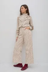 Pantalón de jean con estampado floral pequeño en tonos rosados sobre base crema, de tiro medio-alto y corte recto al tobillo.