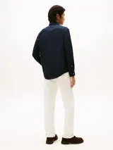 Camisa de manga larga color azul marino, confeccionada en algodón BCI con tecnología non-iron. Presenta cuello clásico, cierre frontal de botones blancos y el logo de Tommy Hilfiger bordado en el pecho.