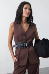 Chaleco sastrero de color marrón, con silueta recta, escote en V y cierre frontal con botones. Presenta una estructura definida y tejido con caída firme.