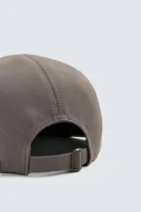 Gorra de seis paneles color marrón topo con visera plana y ojales bordados. Presenta bordado frontal en blanco con el texto "Alternative Lifestyle" y "Trastevere, Rome.".
